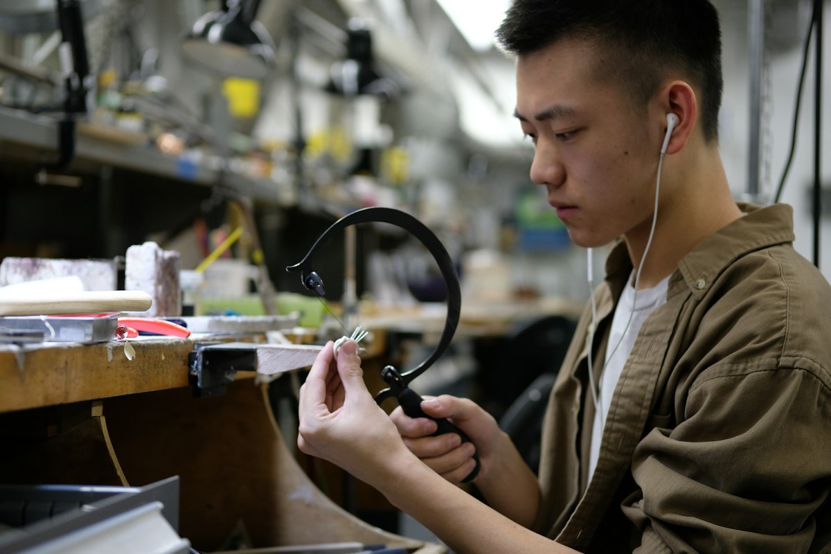 An artisan wire wrapping a custom pendant at the workbench